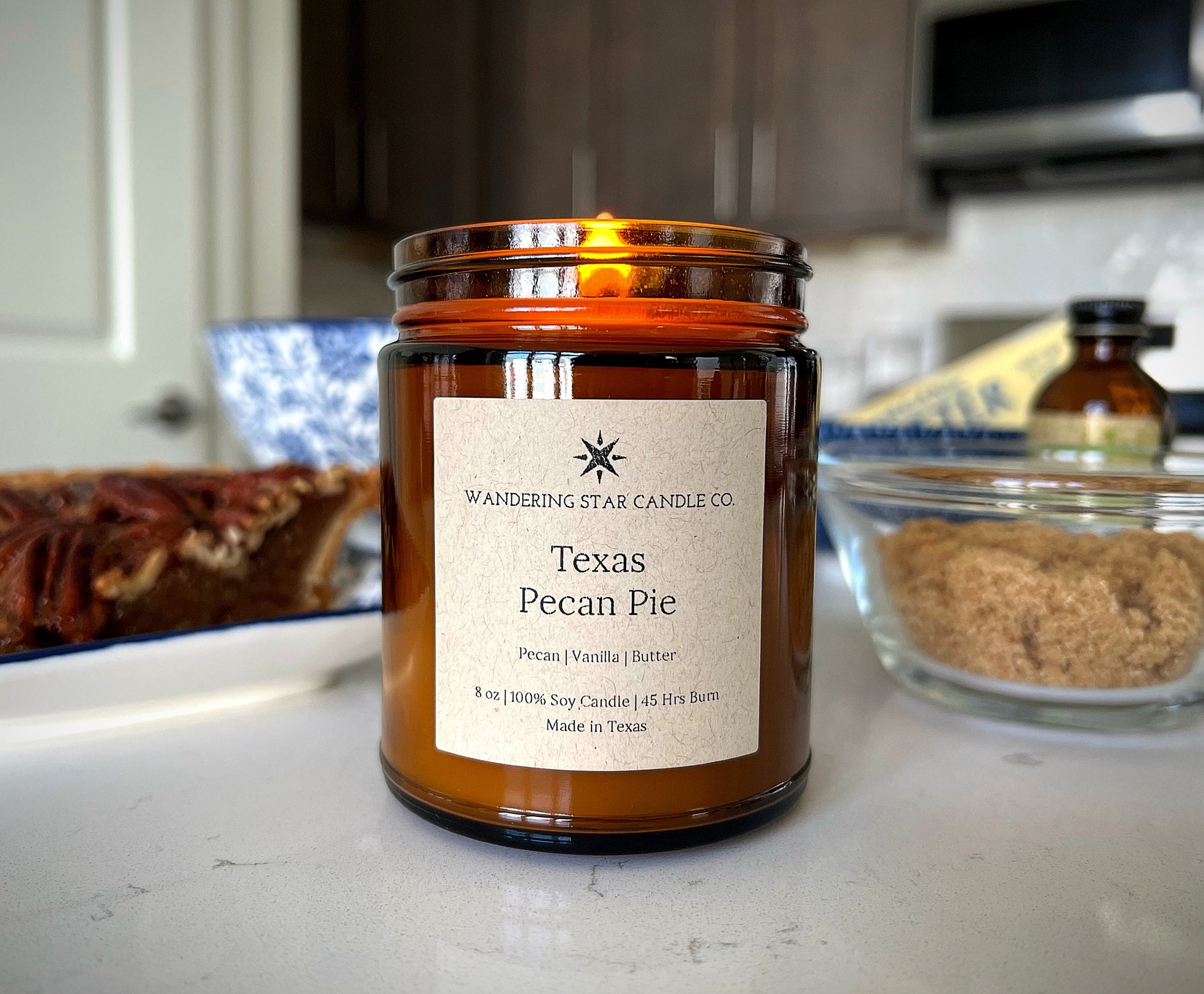 A lit amber jar candle in the scent of Texas Pecan Pie